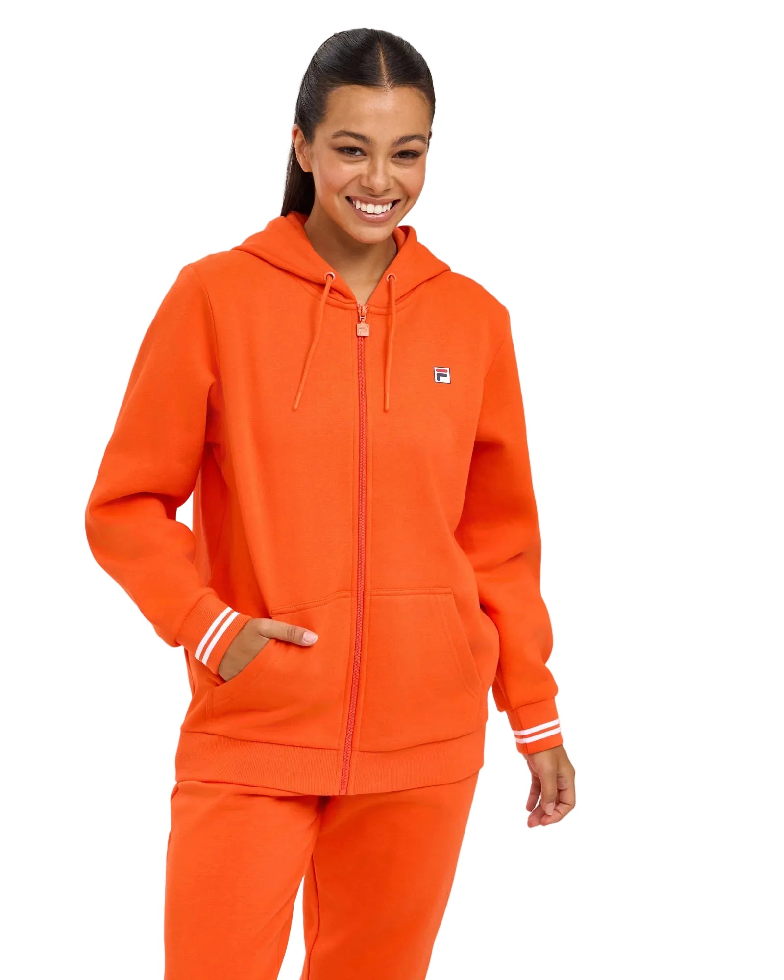 Person wearing an orange tracksuit with a visible brand logo on a light gray background