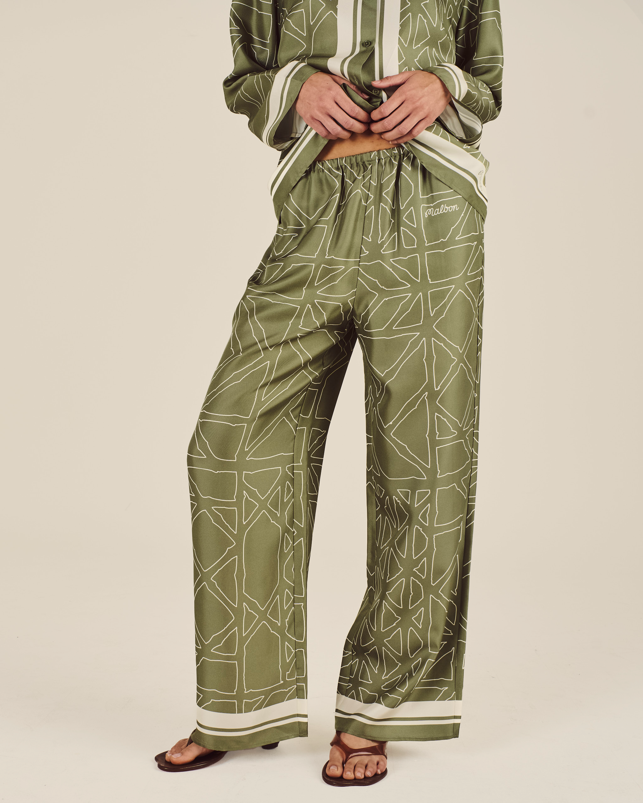 Person wearing a green geometric patterned outfit on a beige background