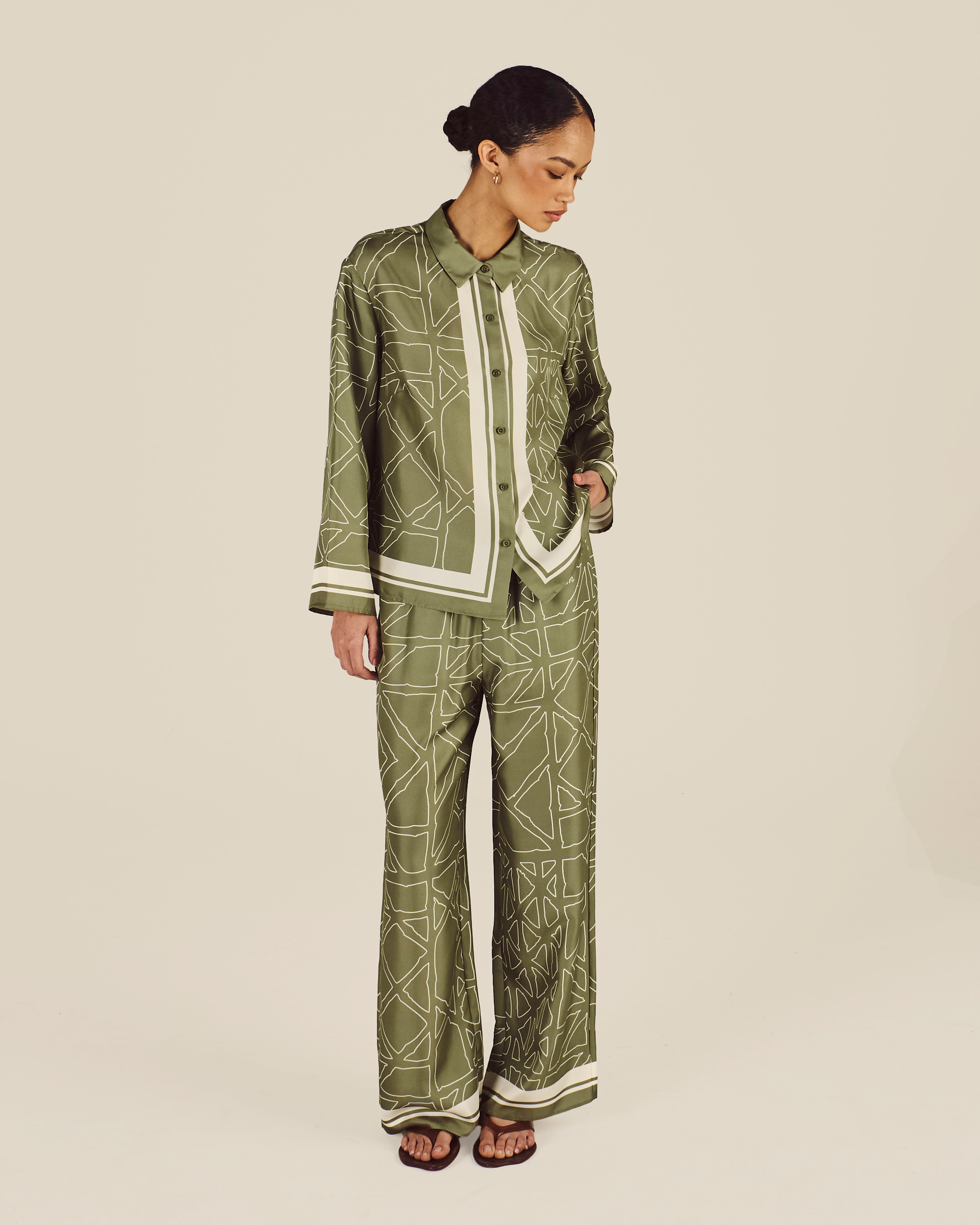 Woman wearing a green patterned outfit on a beige background