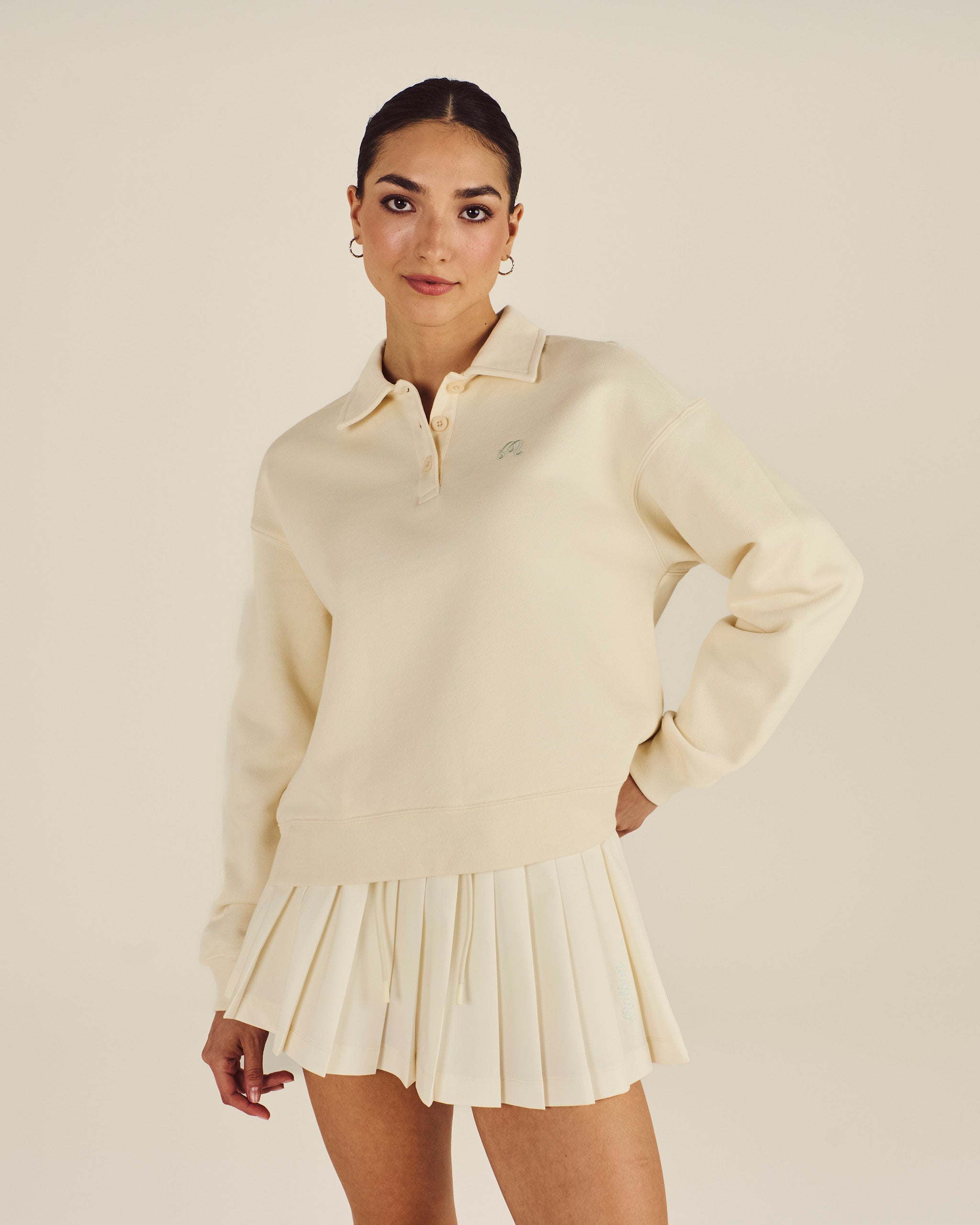 Woman wearing a cream-colored sweater and skirt on a beige background