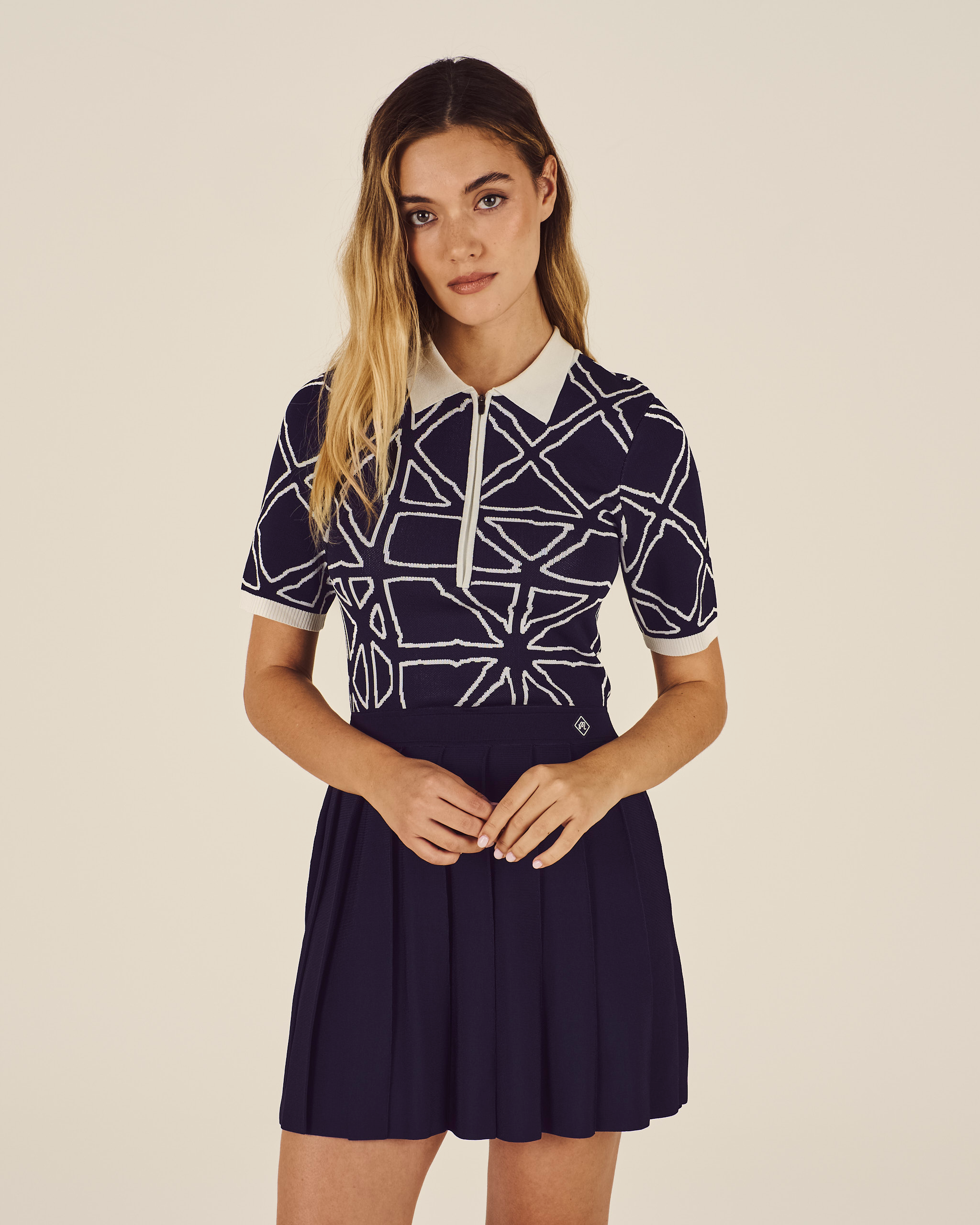 Woman wearing a navy blue dress with white geometric patterns on a beige background