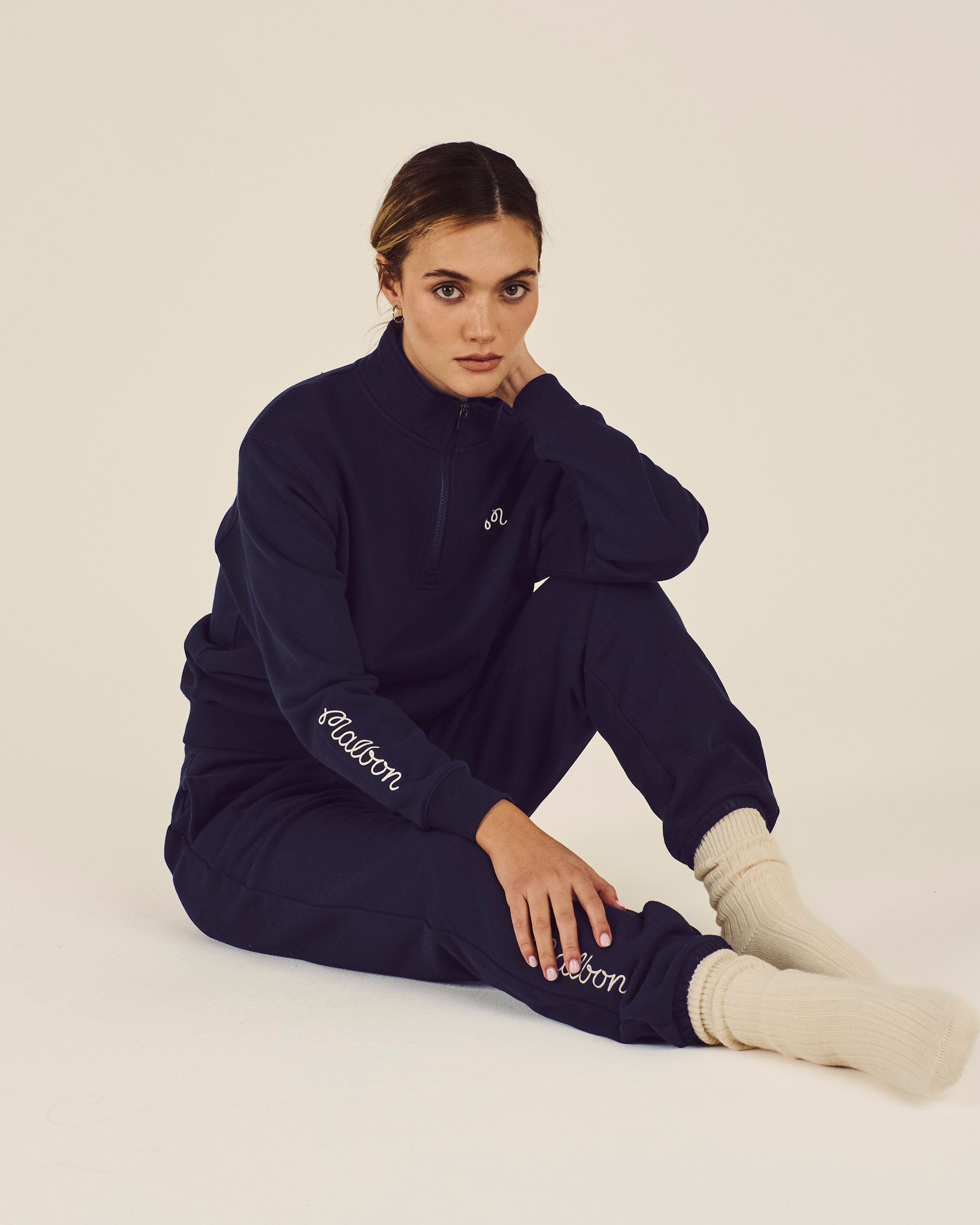 Person wearing a navy tracksuit with 'Rafale' branding on a beige background