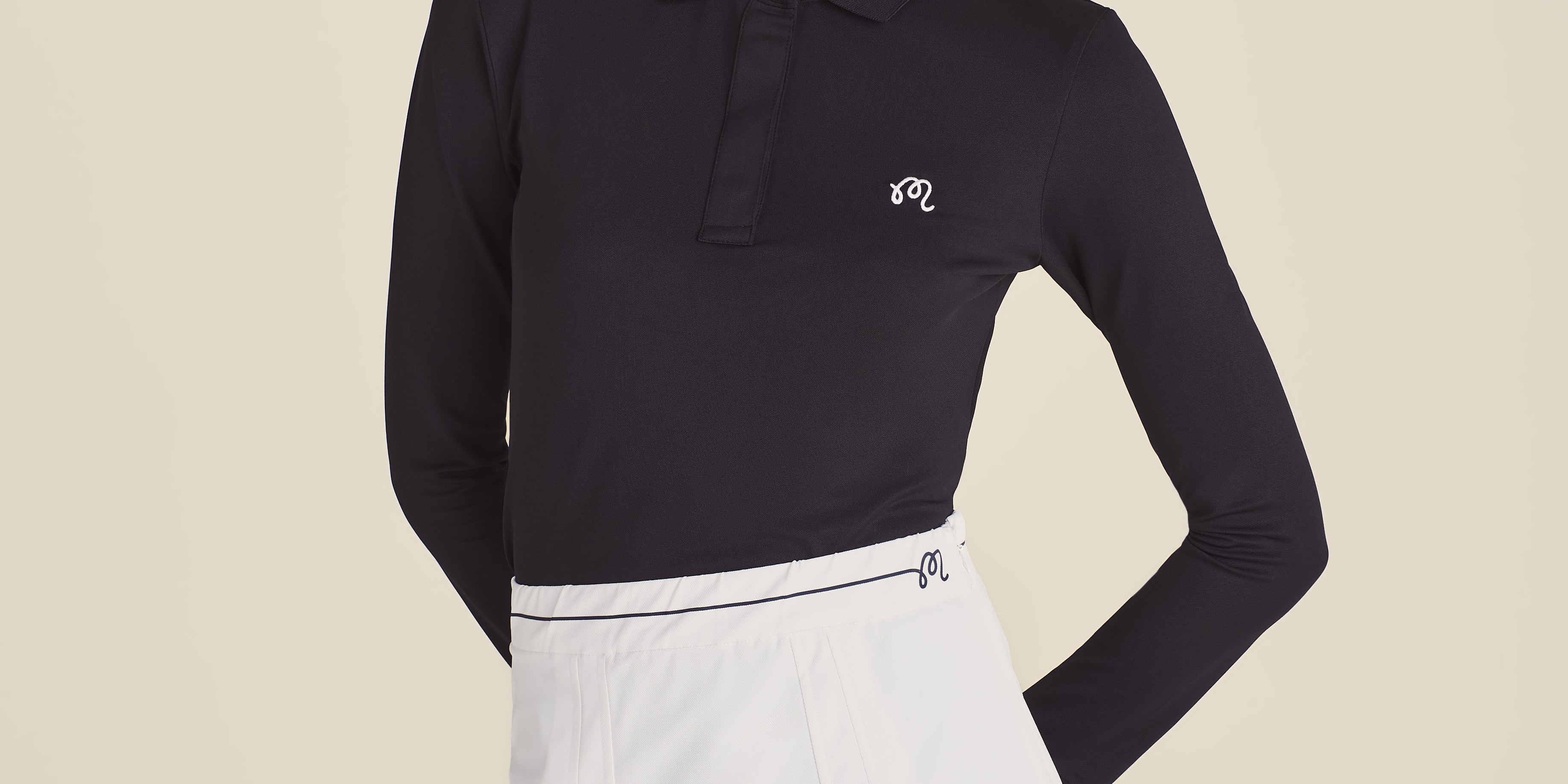 Woman wearing a black long-sleeve polo shirt and white skirt on a beige background