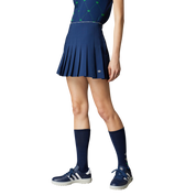 Person wearing a blue tennis outfit with skirt, top, socks, and shoes on a gray background