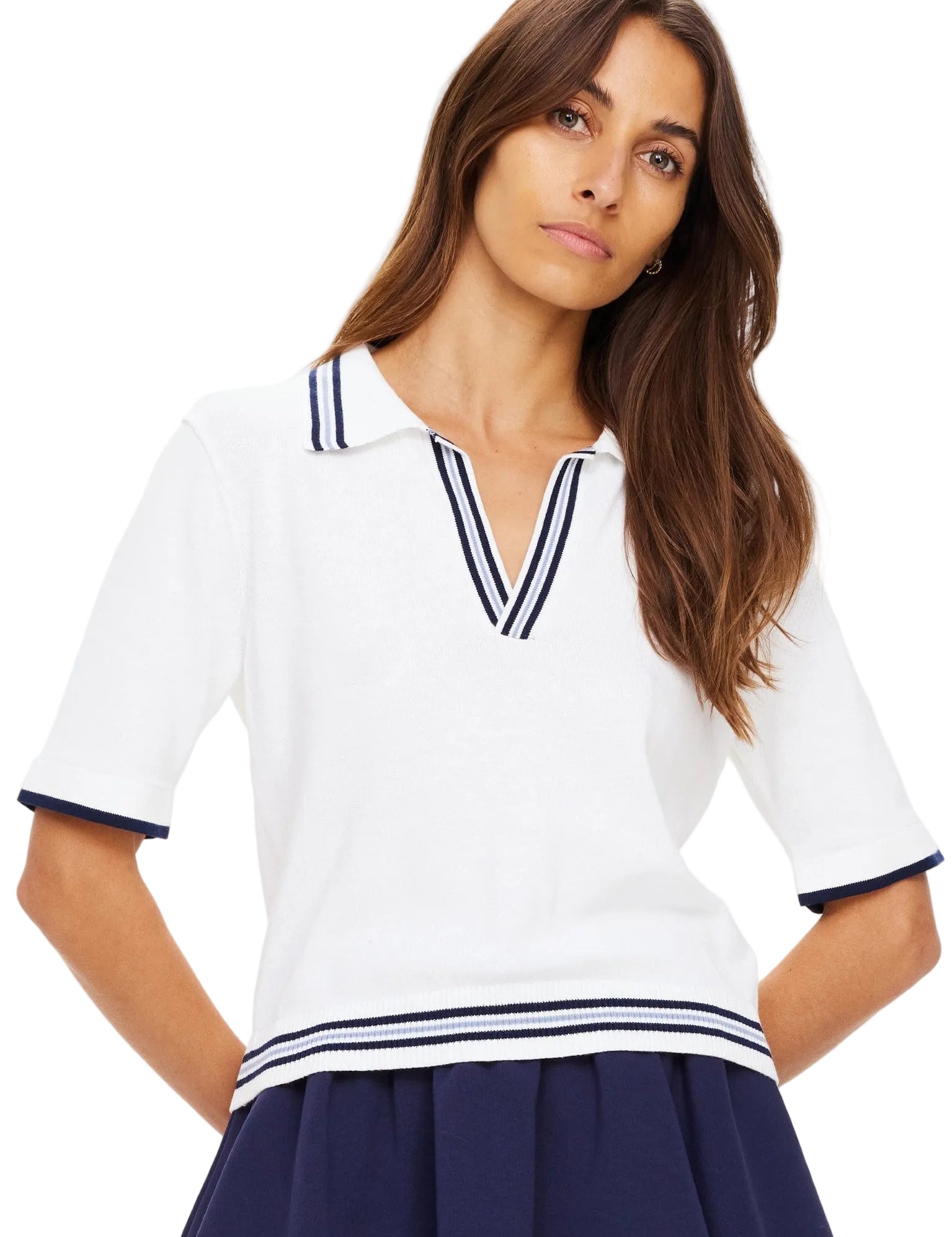 Woman wearing a white polo shirt with navy trim and a navy skirt on a white background