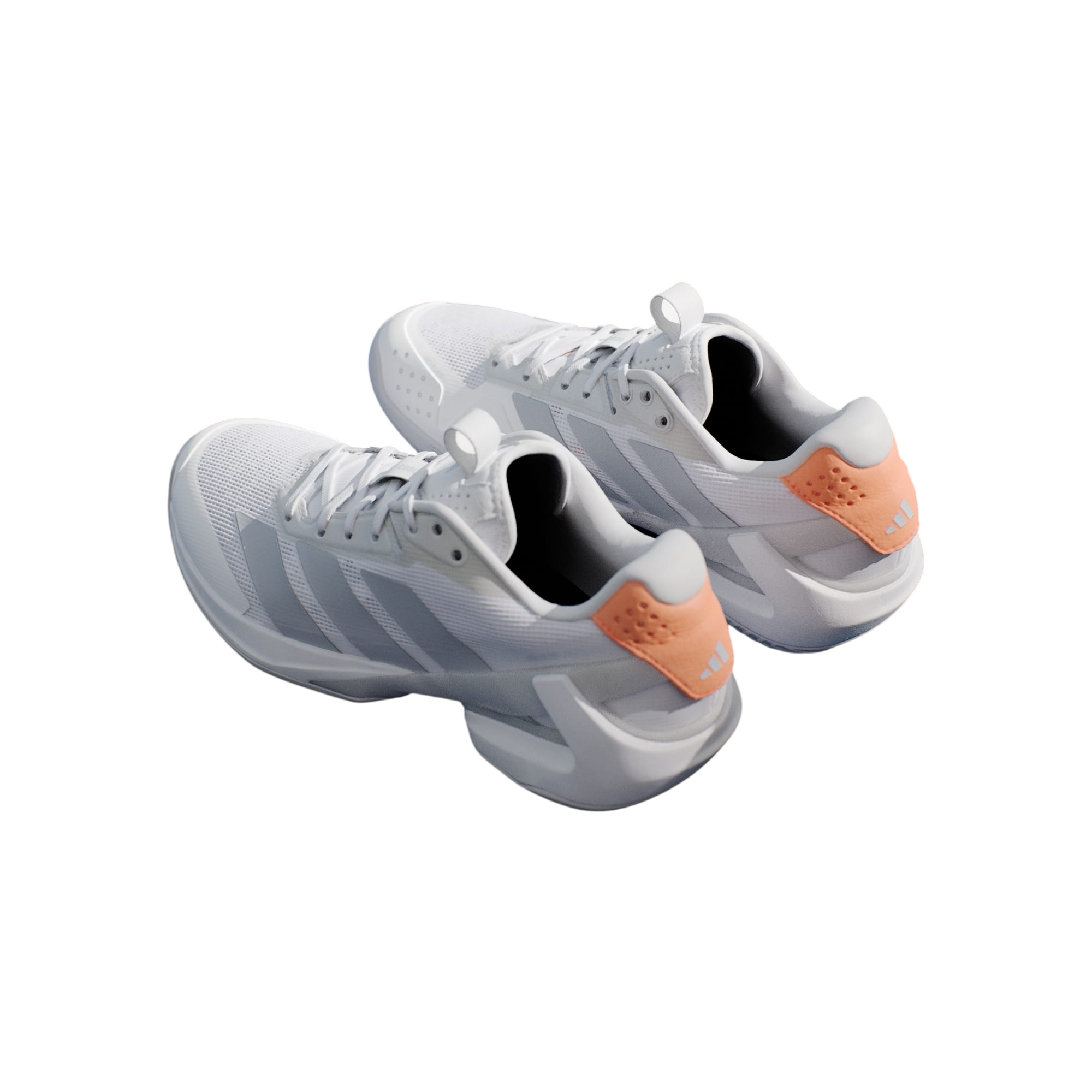 White tennis shoes with orange accents on a blue surface with a tennis racket and ball.