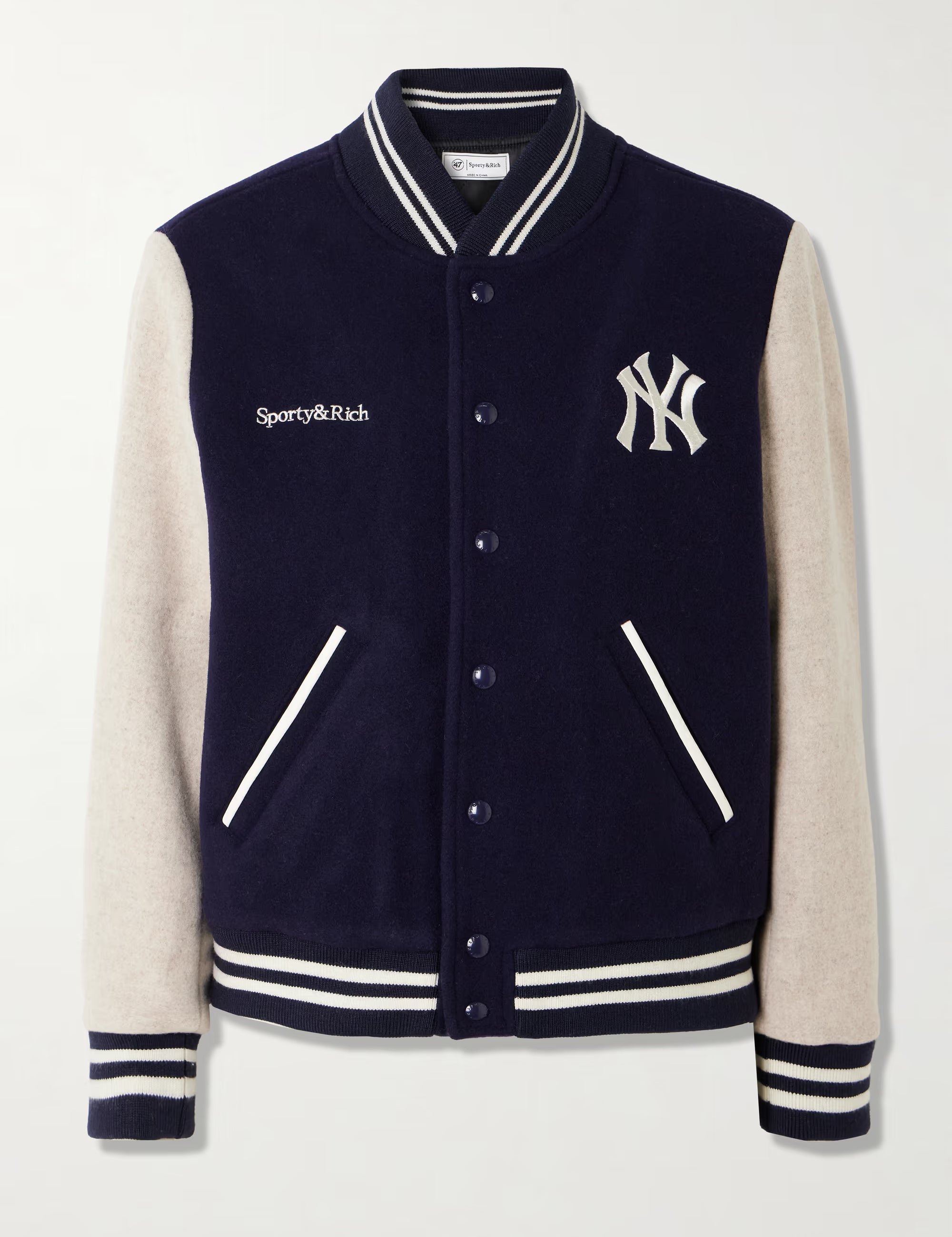 Navy body and beige arms varsity jacket with Sporty & Rich and New York Yankees logos on a white background